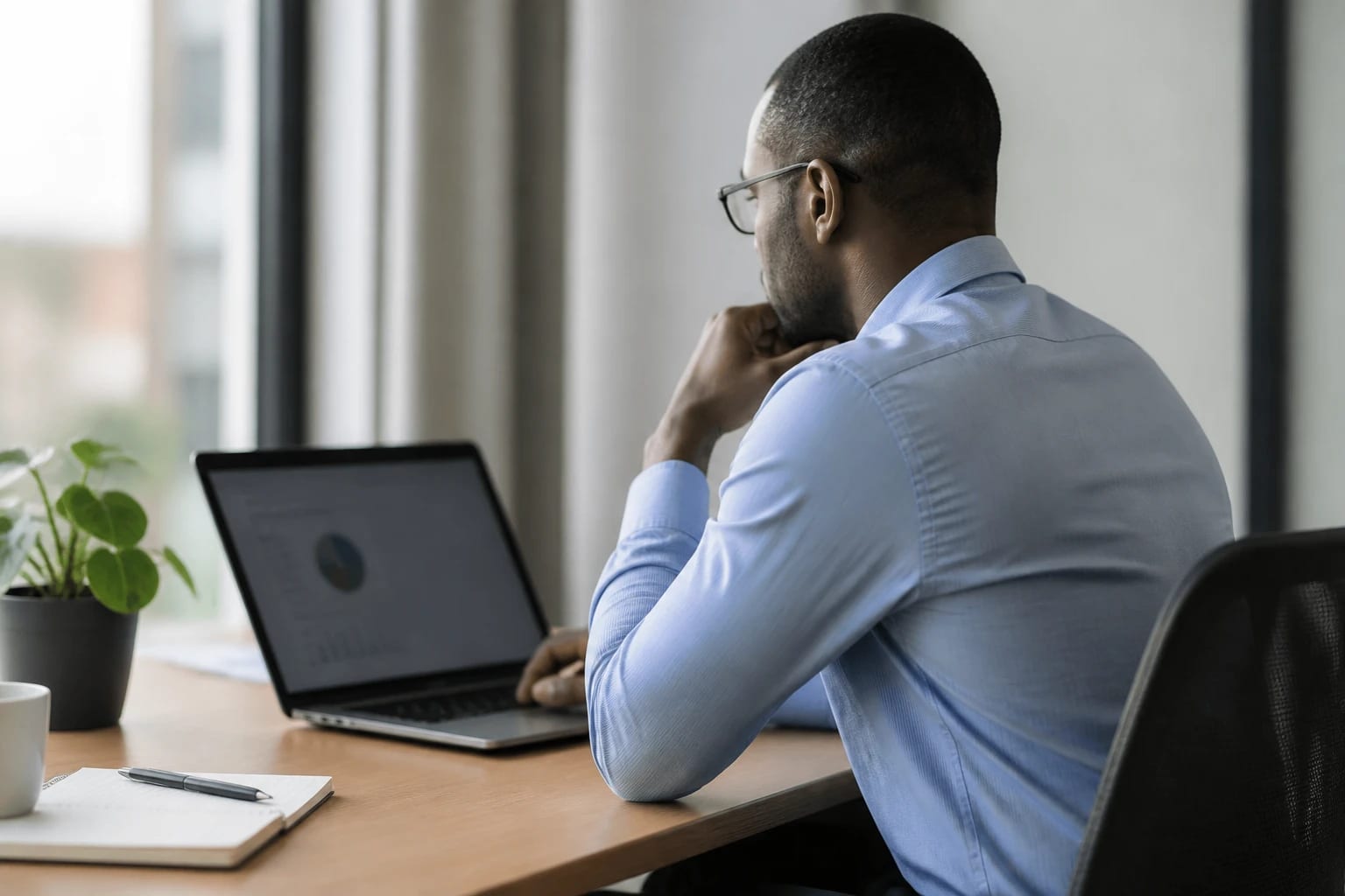 Woman at a desk looking closely at a laptop screen in an office