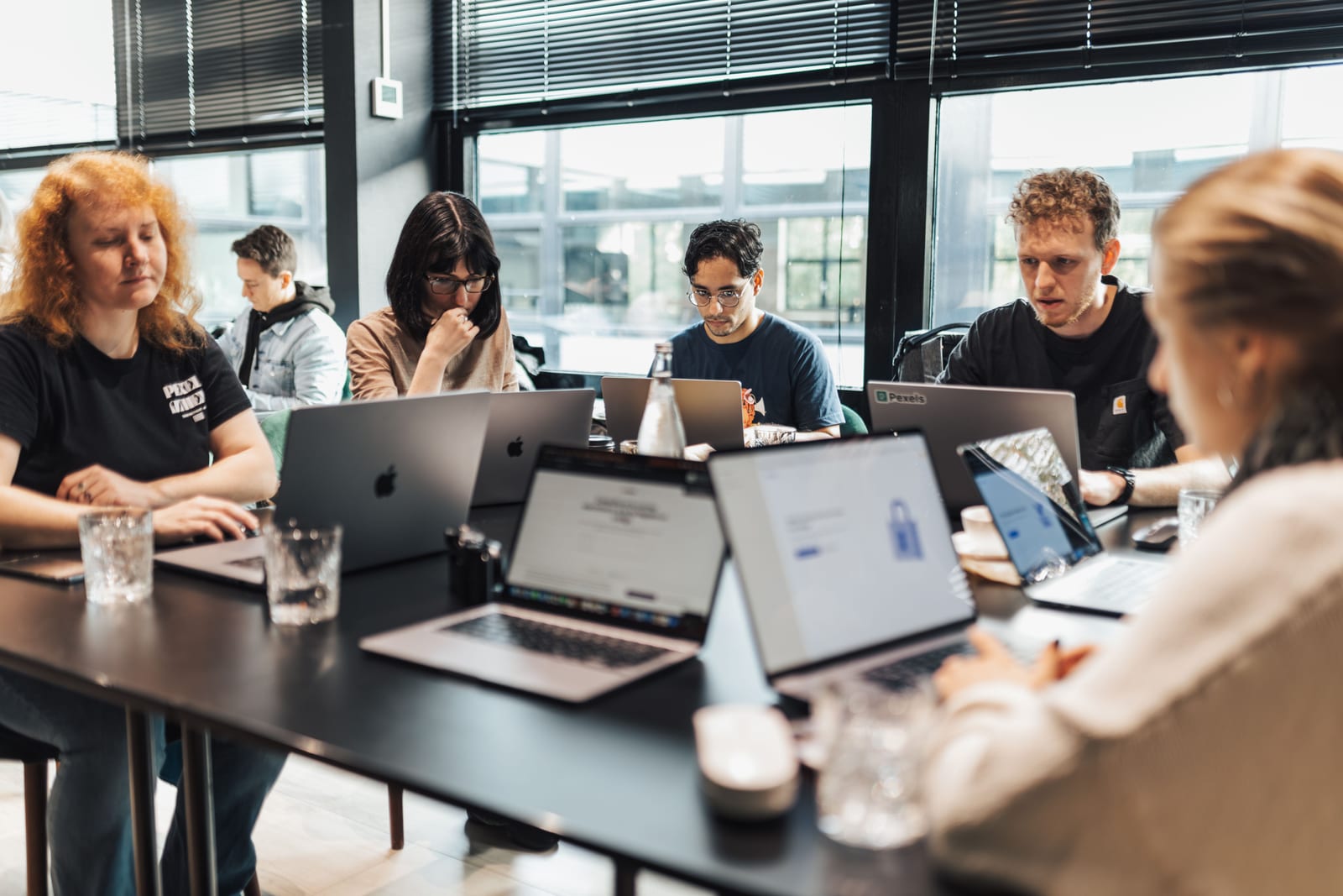 Colleagues gathered around a table with laptops during a team meeting