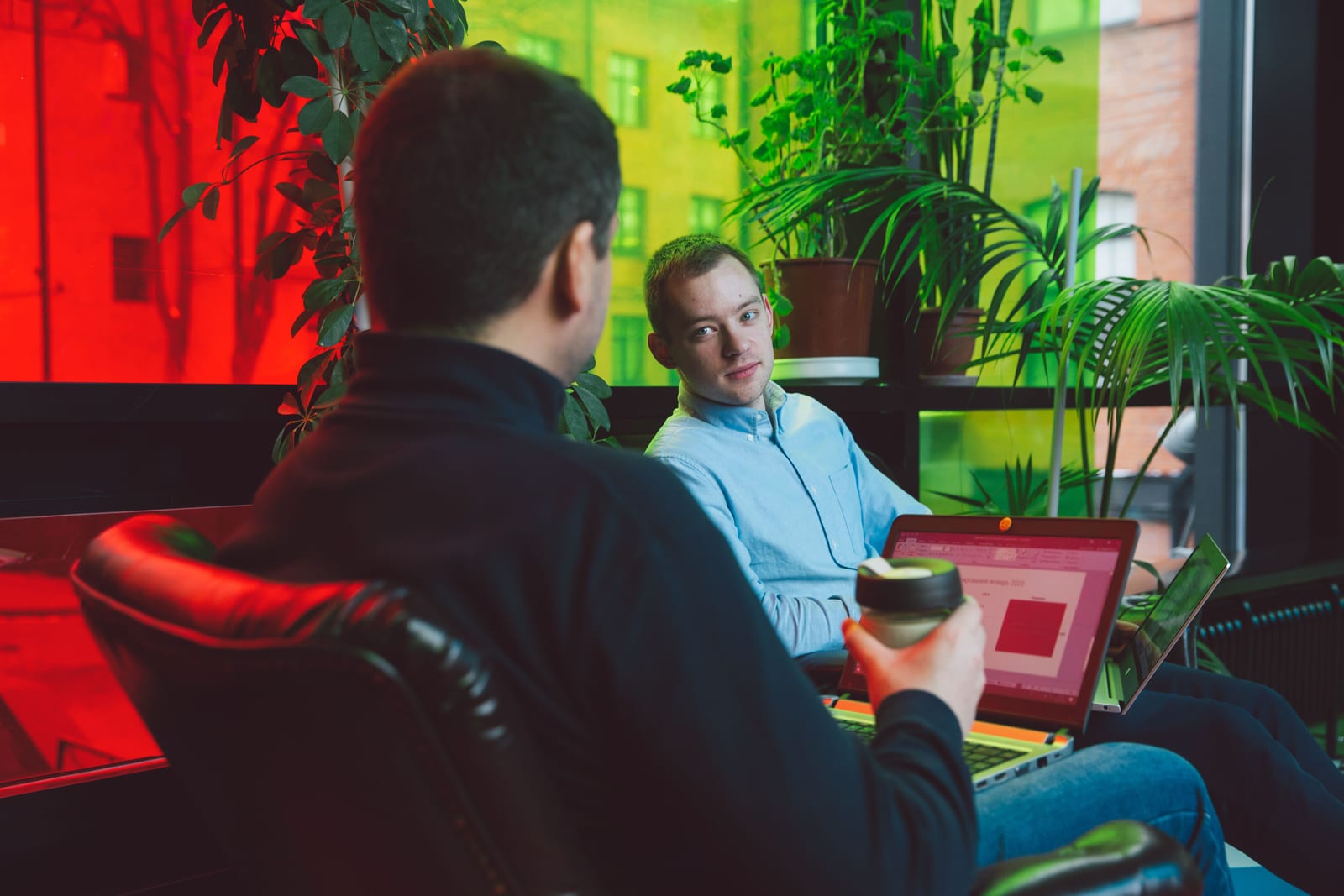 Two colleagues talking over a laptop at a cafe table