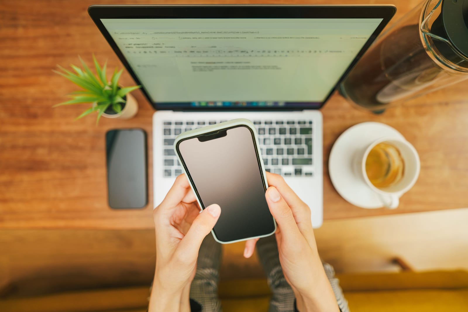 Phone and laptop side by side on a desk showing messaging and feed screens